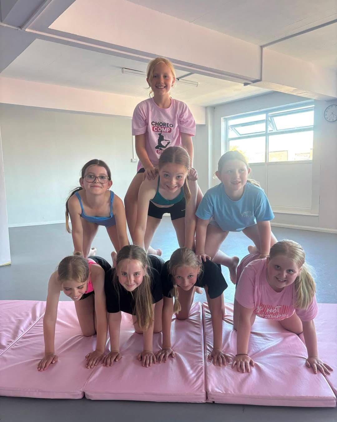 Pupils building a human pyramid on pink crash mats