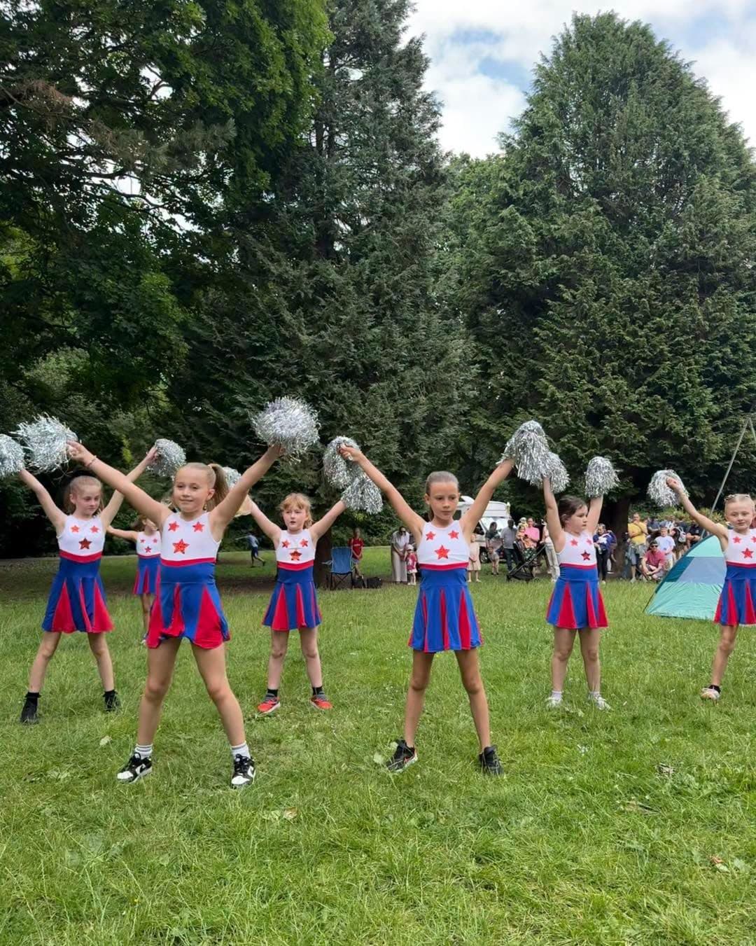 Campers performing a pom-pom routine on the grass in the park