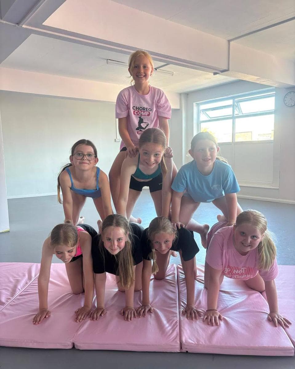 Pupils building a human pyramid on pink crash mats