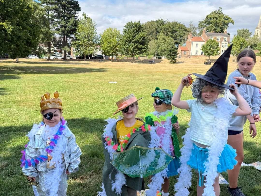 Campers in fancy dress in the park, one in a witch's hat