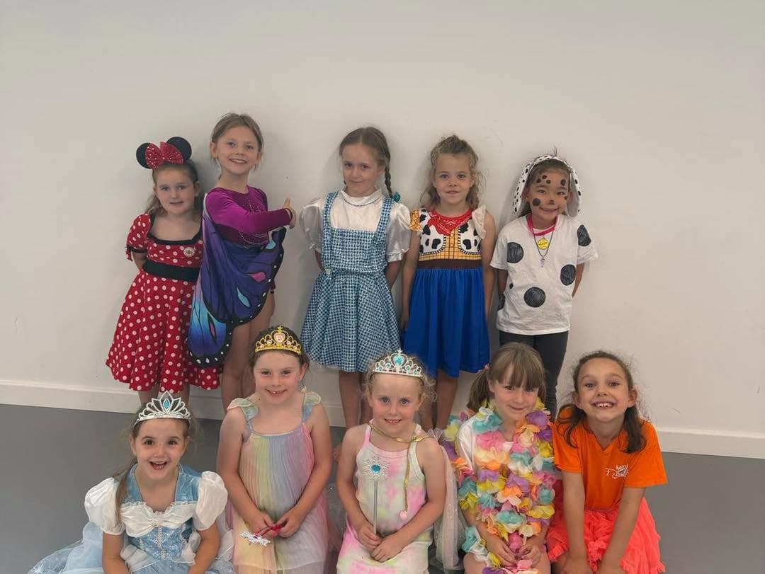 Children in Disney costumes posing against a white wall
