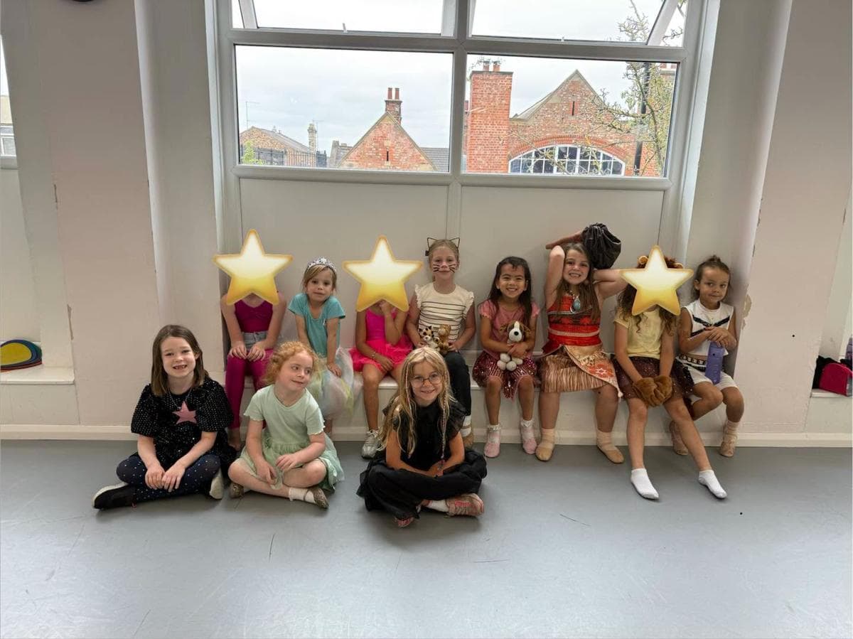 Campers sitting on the studio floor holding gold star props