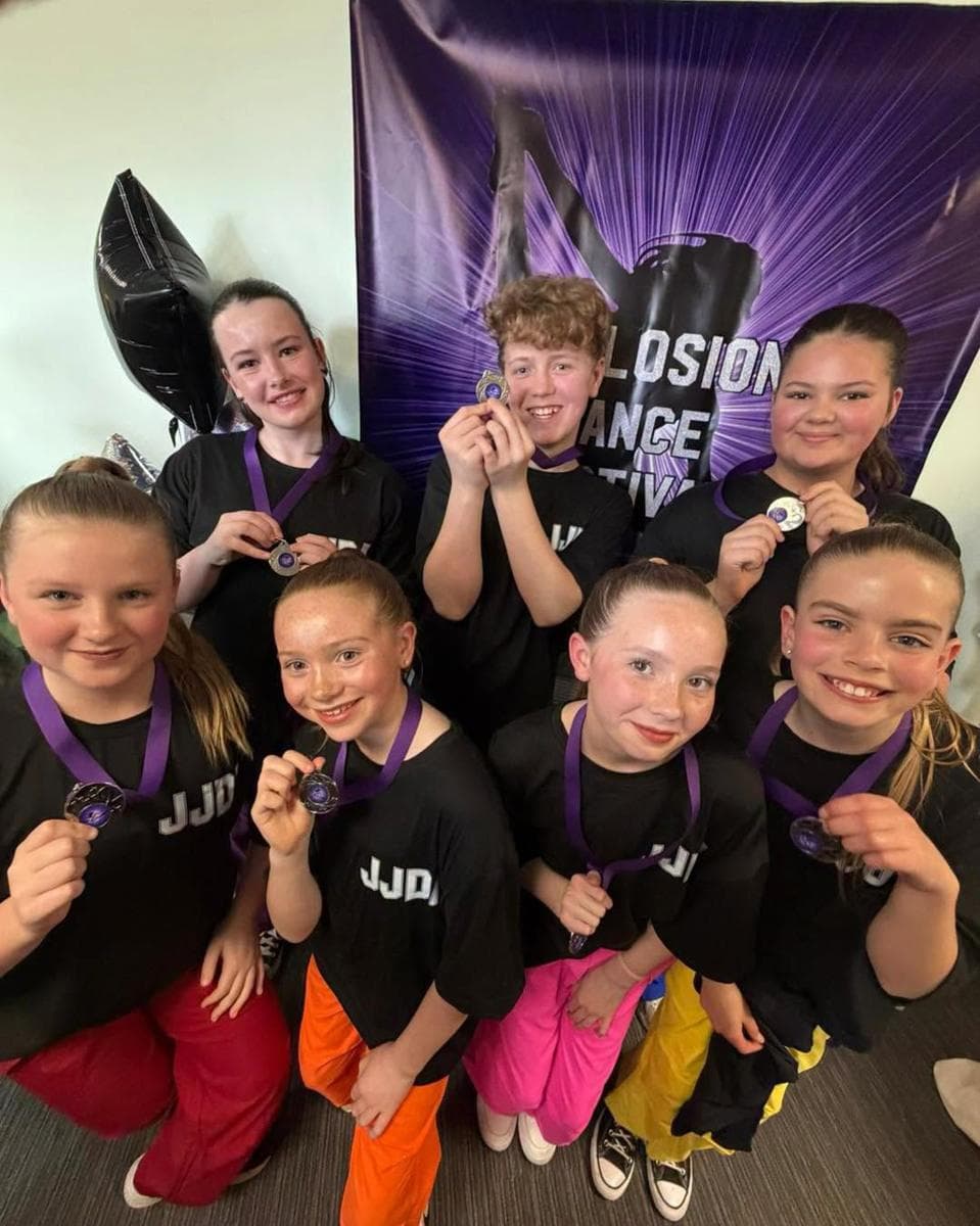 Competition dancers in JJDA T-shirts holding up their medals