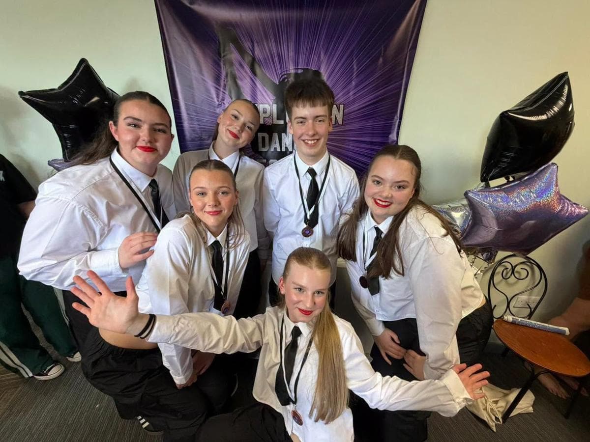 Competition dancers in white shirts and ties with star balloons