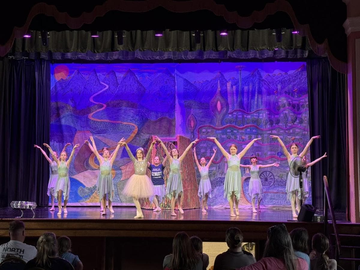 Dancers performing in front of a painted castle backdrop