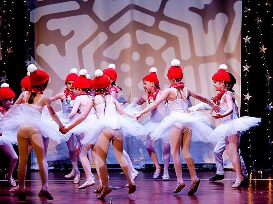Dancers in white tutus and red hats on stage