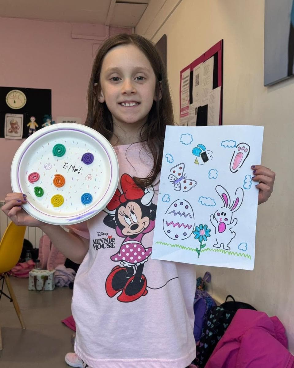 A girl proudly holding up her Easter crafts