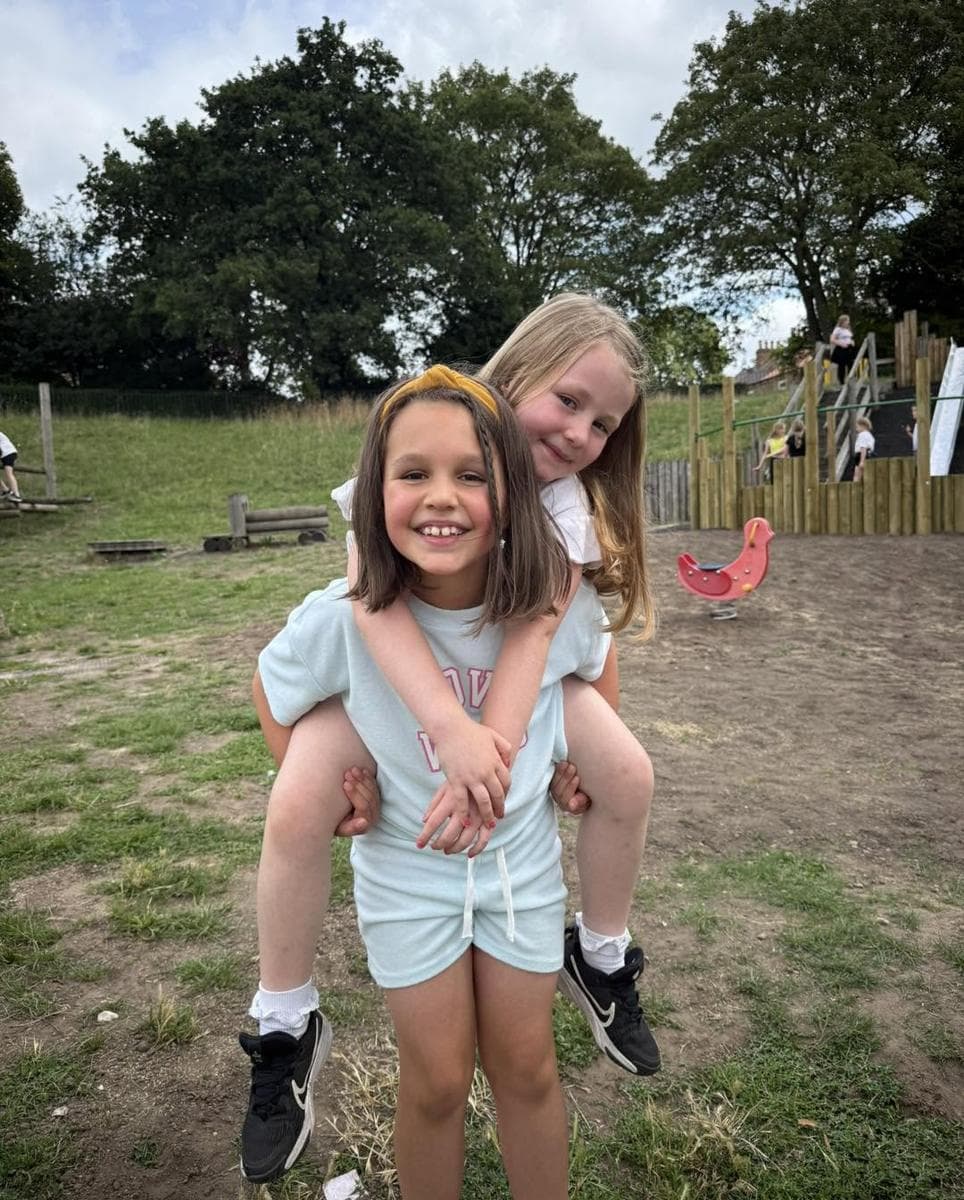 One girl giving another a piggyback in the park