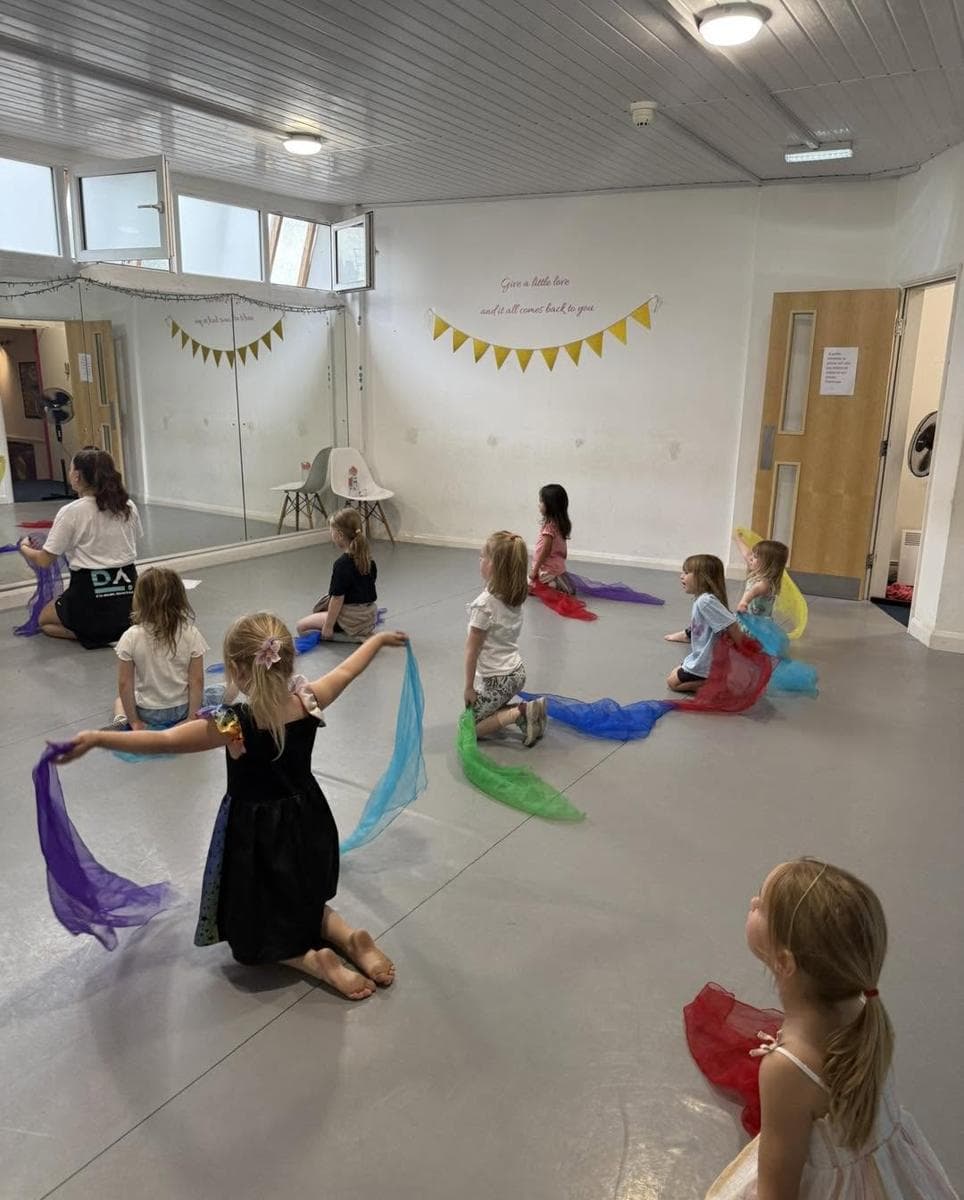 A young class dancing with coloured scarves