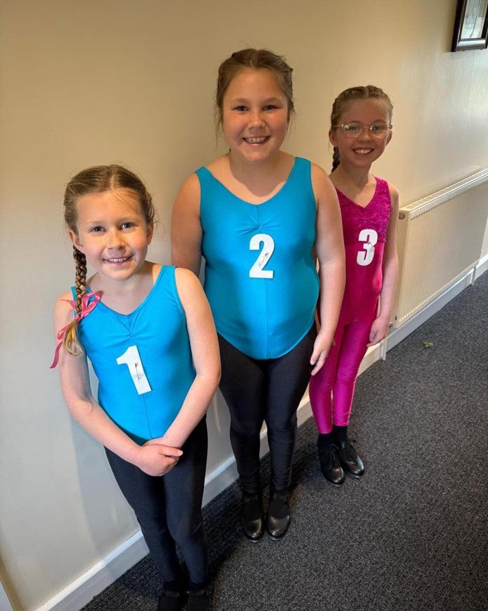 Three pupils in leotards with numbers