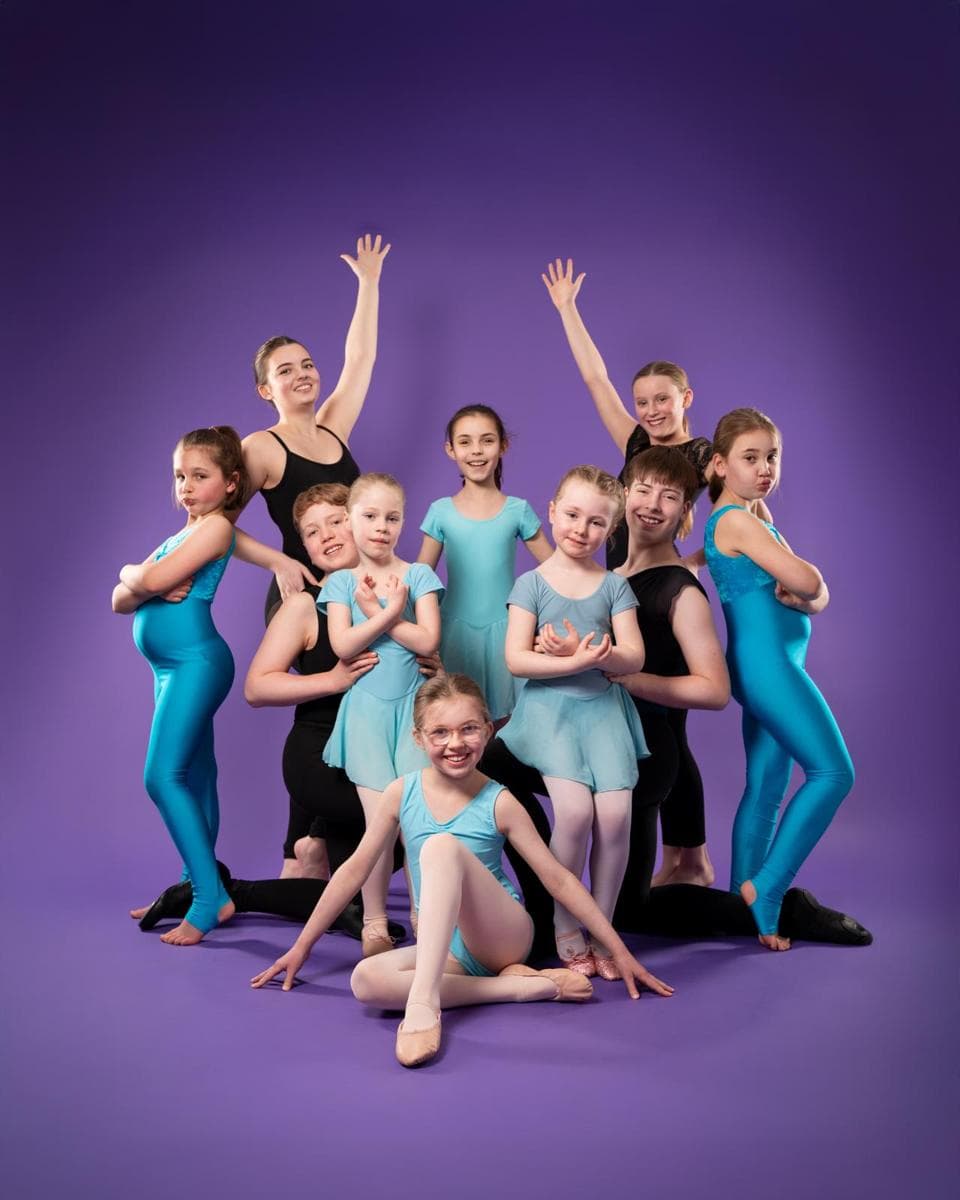 A group of dancers in turquoise and black posing on a purple backdrop