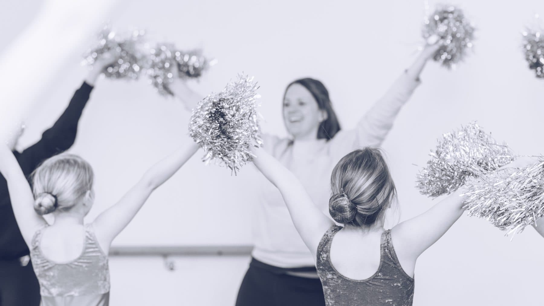 Young dancers waving silver pom-poms with their teacher