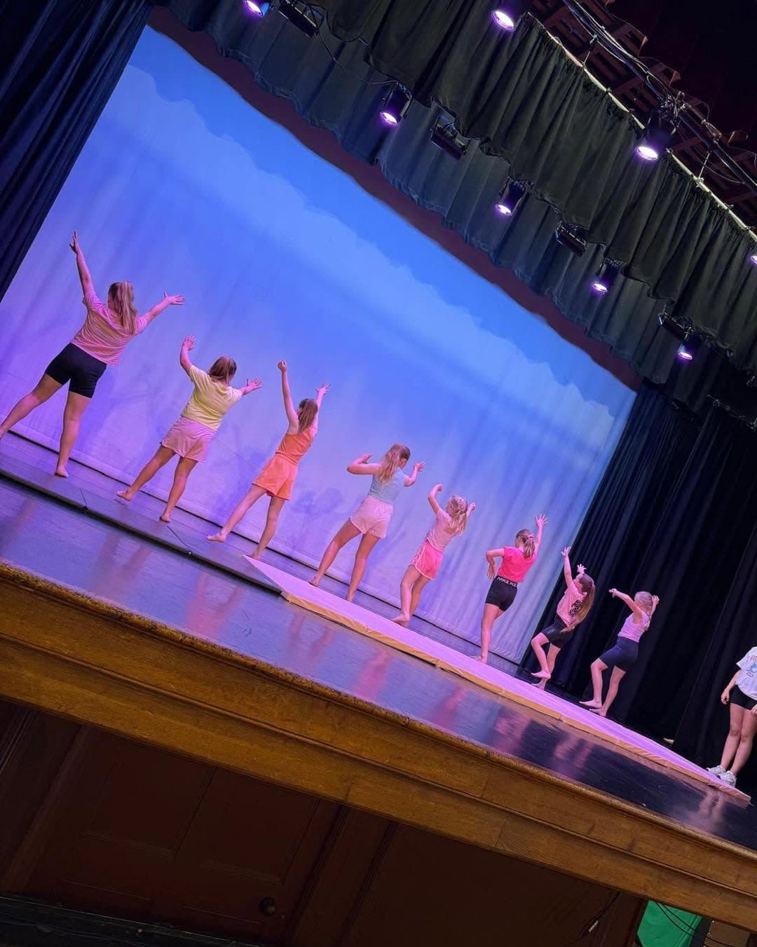 Dancers performing on stage under blue light