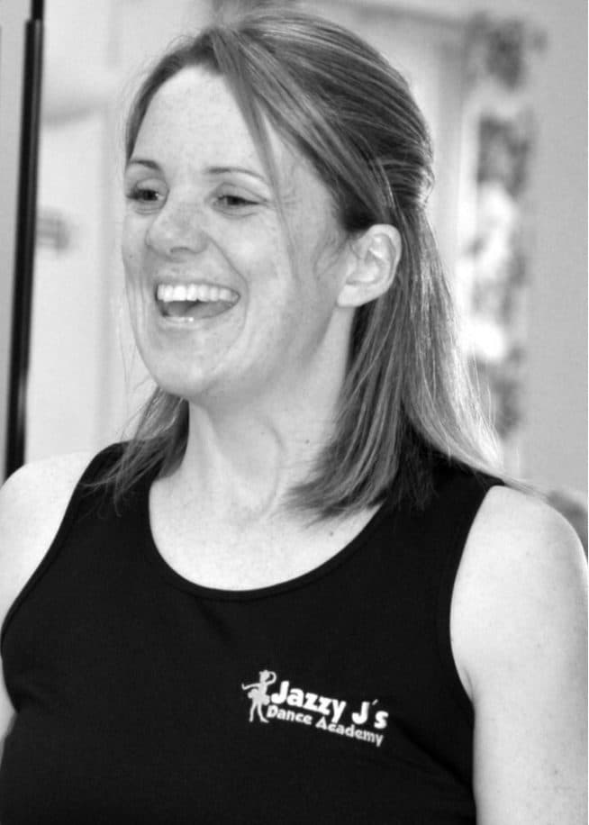 Jess, Principal of Jazzy J's, smiling in a Jazzy J's vest top